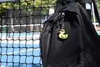 Pixel rubber duck keychain clipped to a black backpack zipper outdoors near a tennis court by LayerPlay