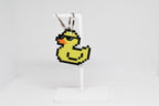 3D printed retro pixel rubber duck wearing sunglasses keychain hanging on a white display stand by LayerPlay