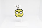 3D printed retro pixelated rolling eyes emoji keychain hanging on a white display stand by LayerPlay
