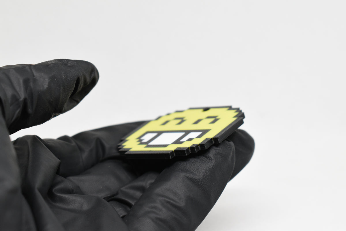 Side angle view showing 3D layered pixel detail and thickness of pixelated smiling emoji keychain by LayerPlay