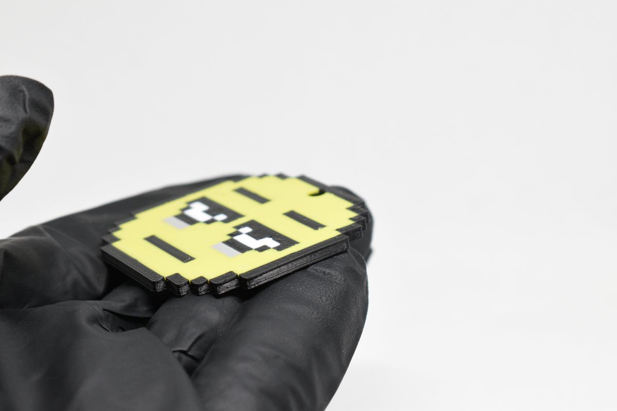 Side angle view showing 3D layered pixel detail and thickness of pixelated tired emoji keychain by LayerPlay