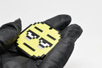 Hand in black glove holding 3D printed pixel tired emoji keychain front view detail by LayerPlay