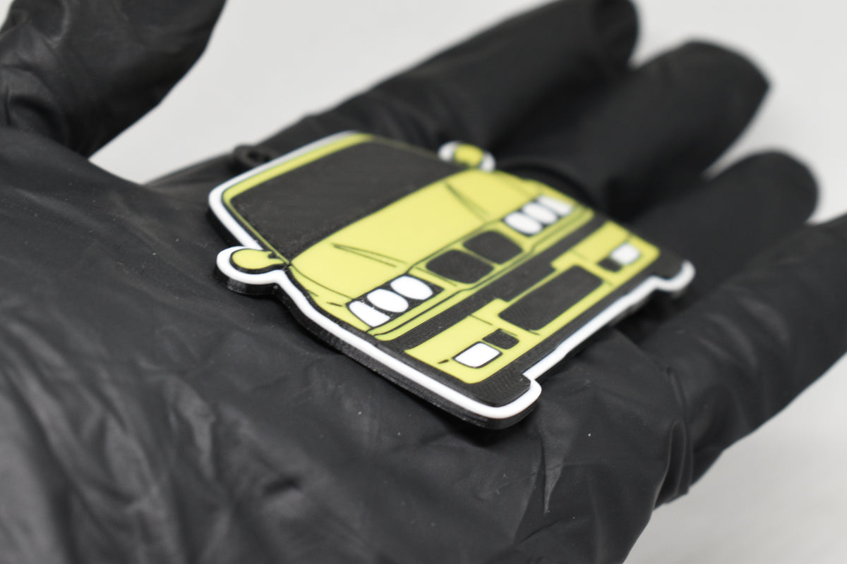 Side angle view showing 3D layered detail of yellow BMW M3 E36 keychain by LayerPlay Pocket Motors