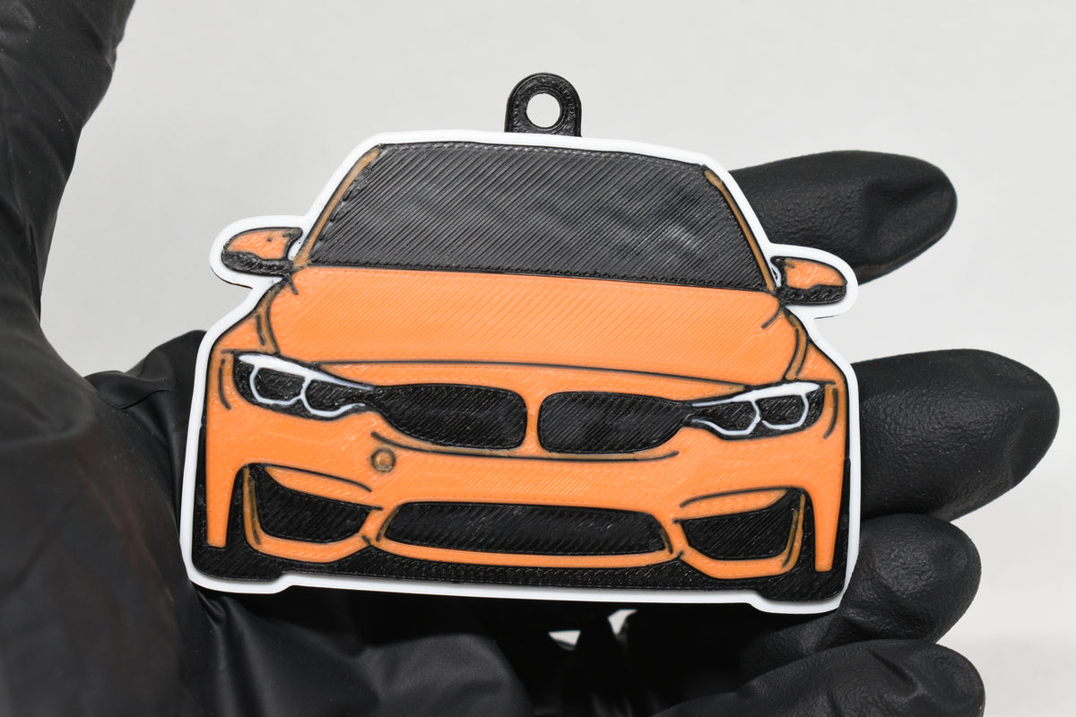 3D printed orange BMW M3 F80 keychain held in hand, front view detail by LayerPlay Pocket Motors