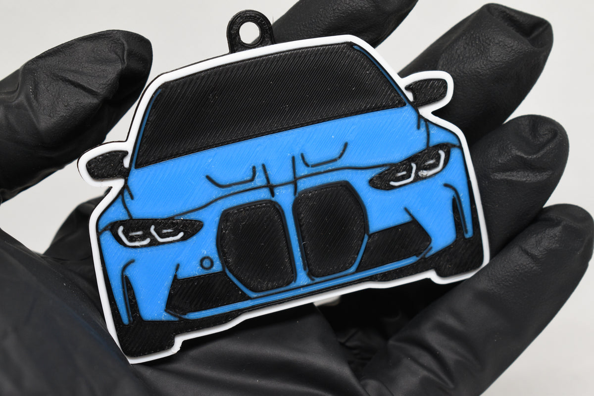 3D printed light blue BMW M3 G80 keychain held in hand, front view detail by LayerPlay Pocket Motors