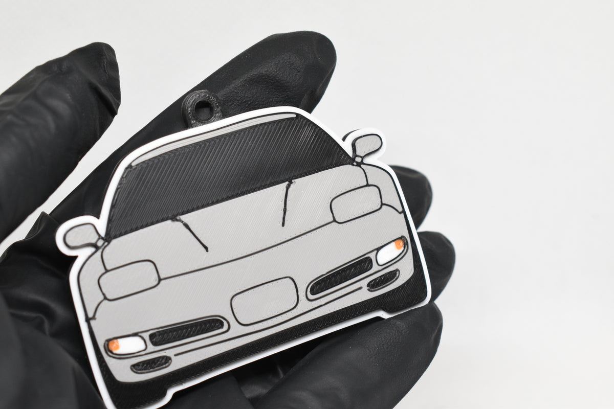 3D printed light gray Chevrolet Corvette C5 keychain held in hand, front view detail by LayerPlay Pocket Motors