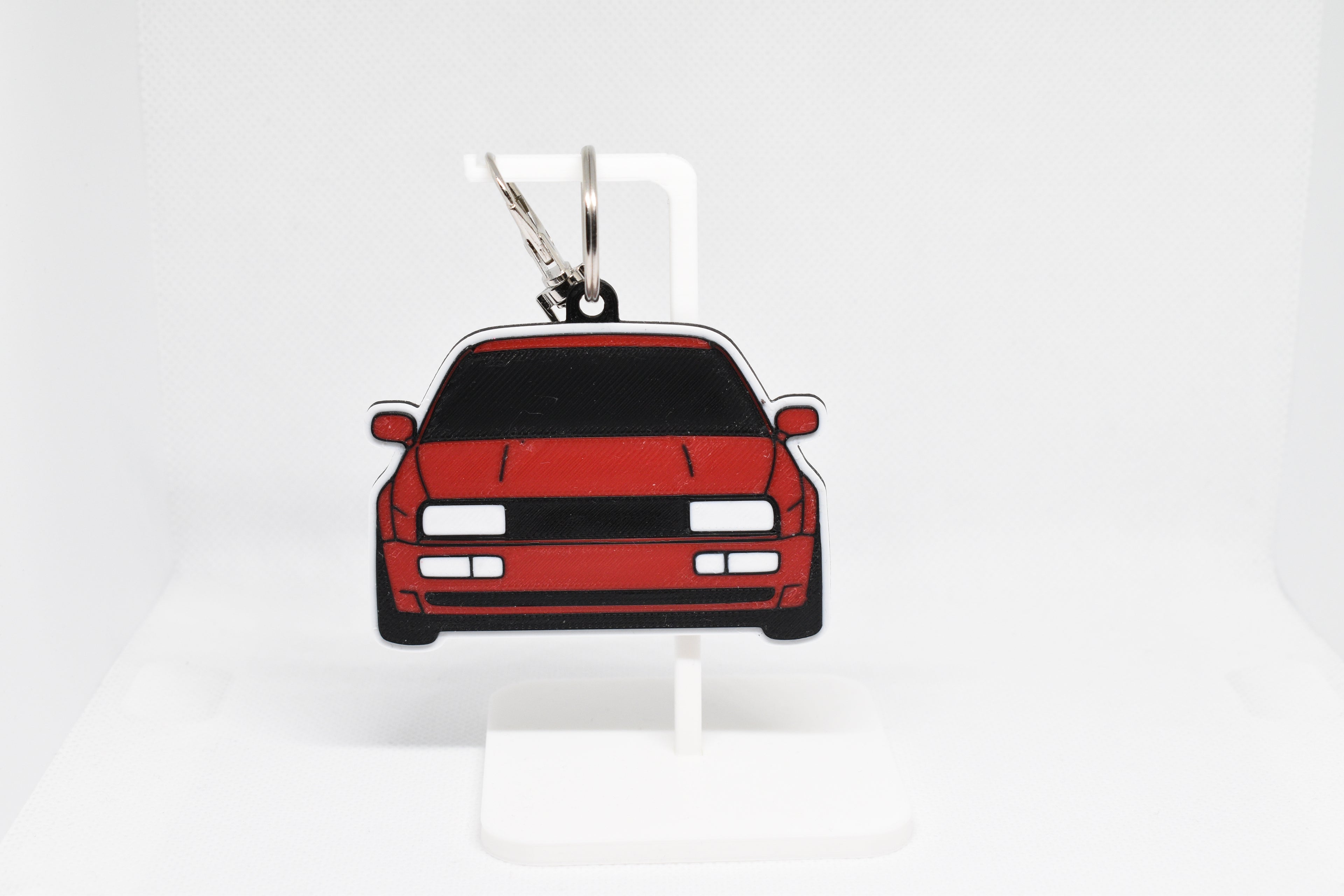 Pocket Motors Corrado keychain displayed on a white stand with metal ring and clip.