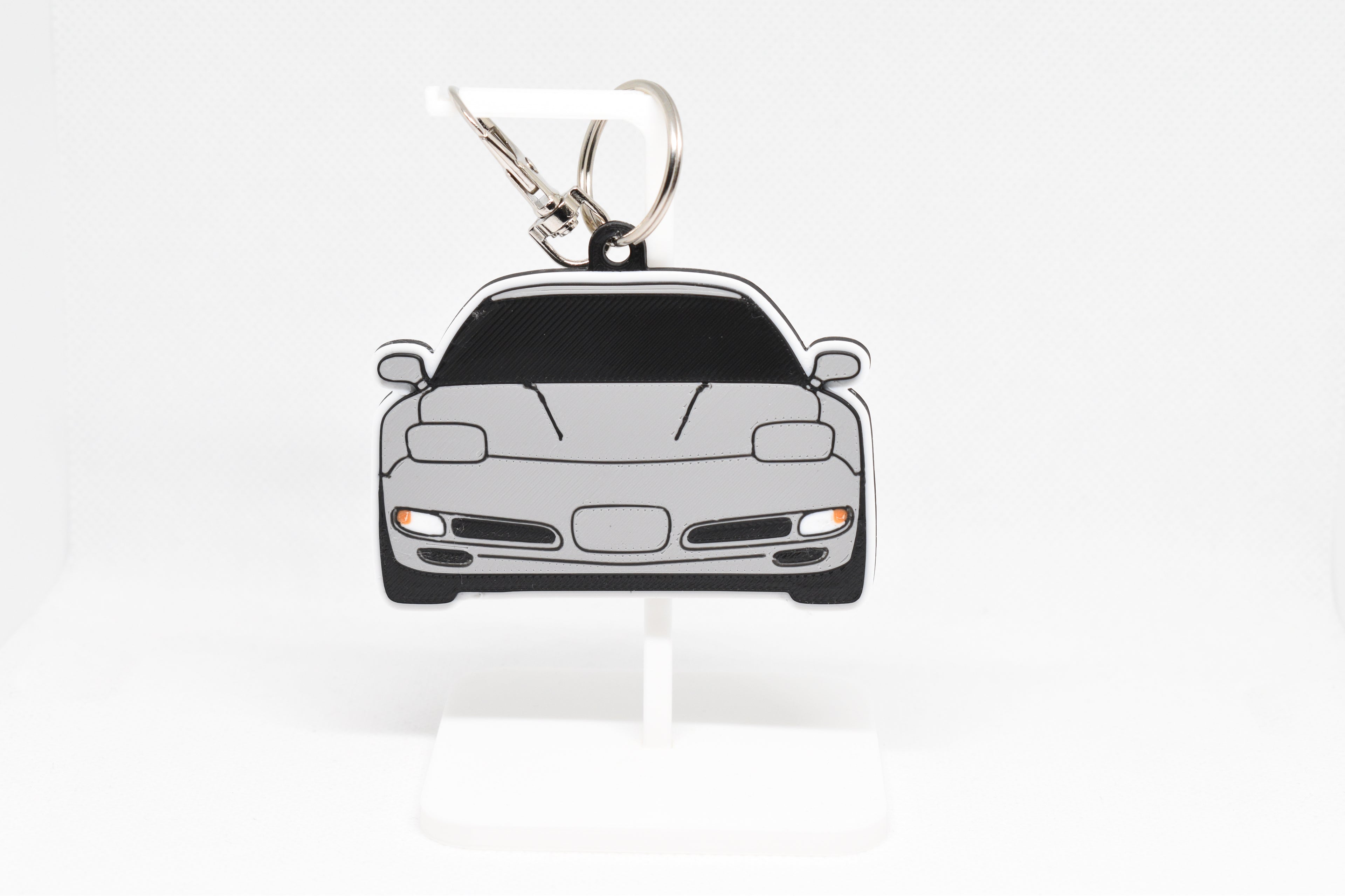 Pocket Motors Corvette C5 keychain displayed on a white stand with metal ring and clip.