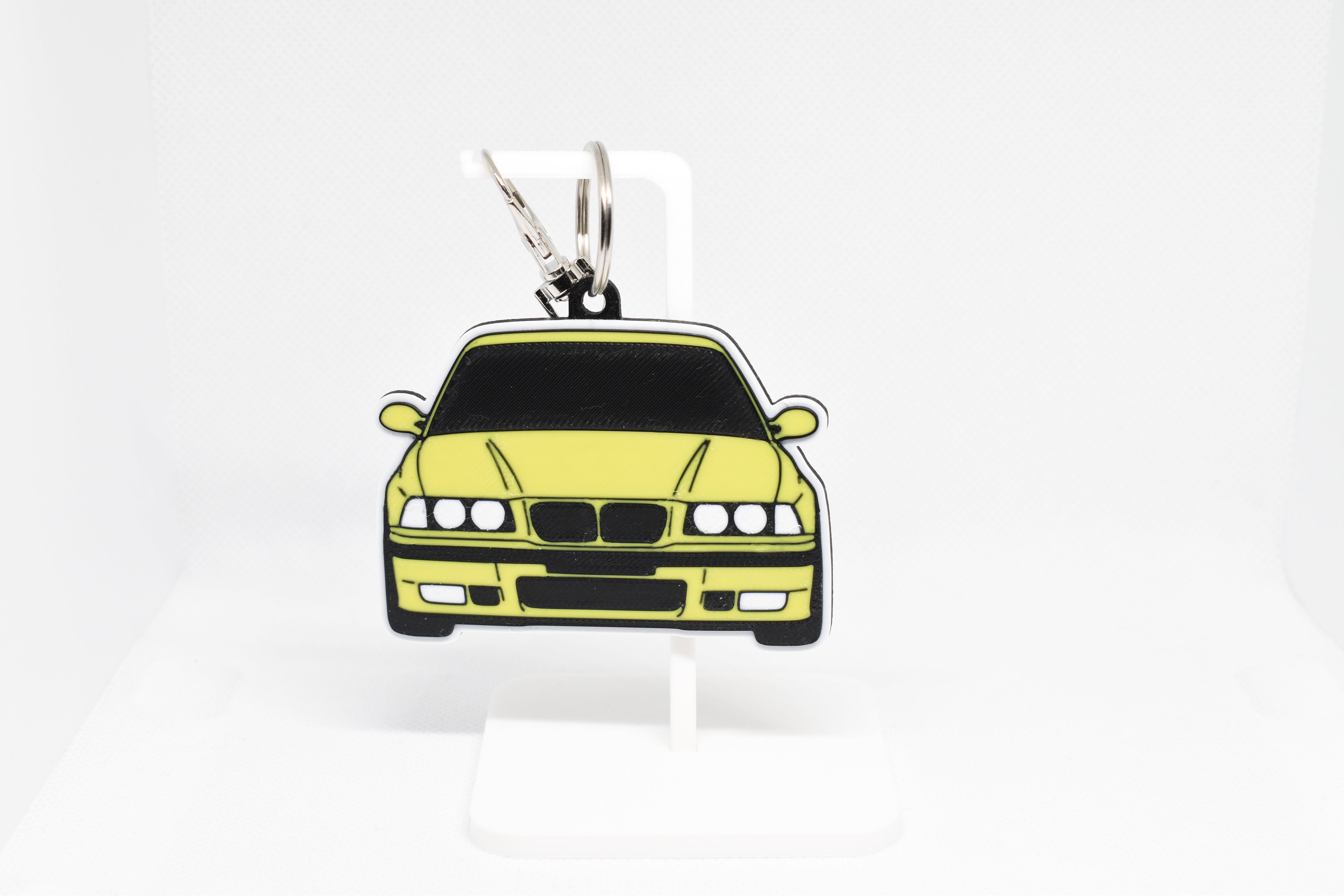 Pocket Motors E36 M3 keychain displayed on a white stand with metal ring and clip.