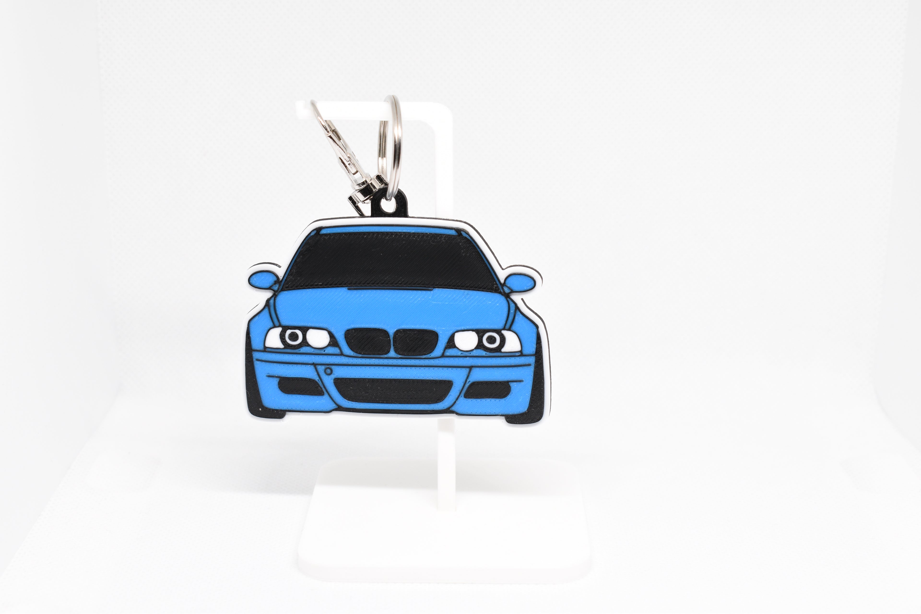 Pocket Motors E46 M3 keychain displayed on a white stand with metal ring and clip.