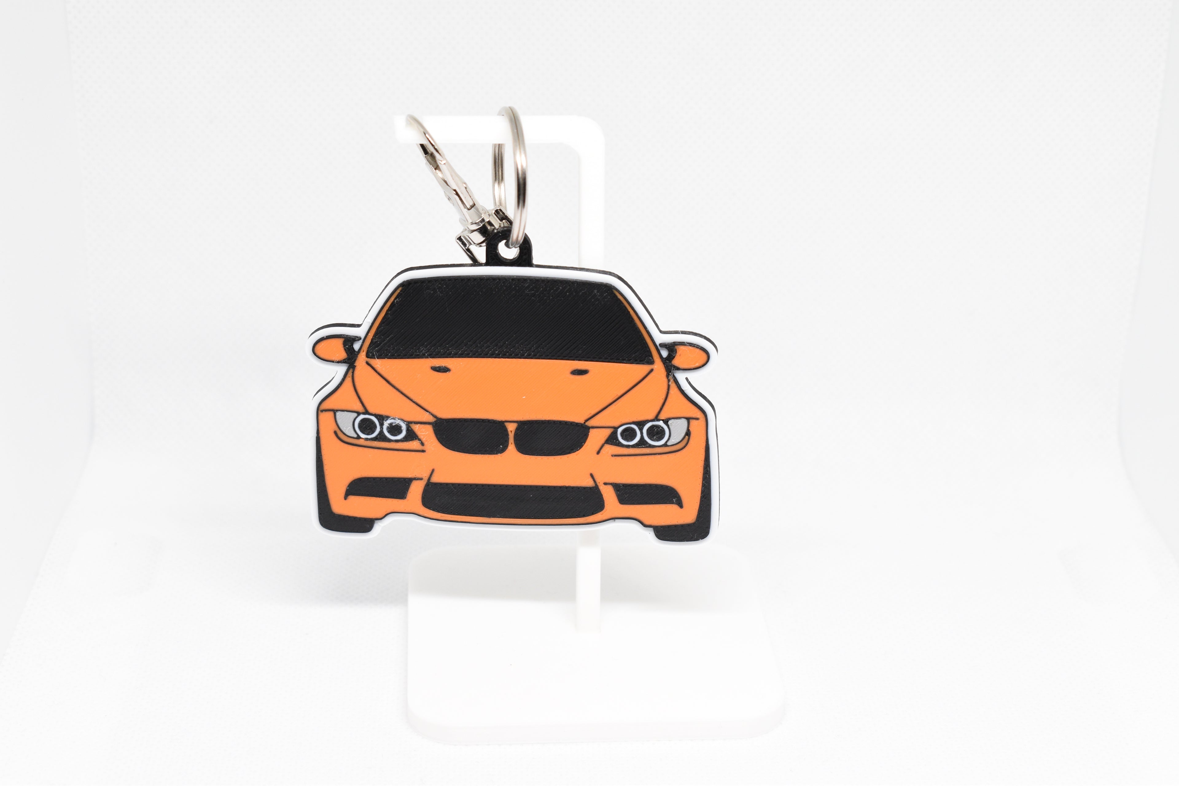 Pocket Motors E92 M3 keychain displayed on a white stand with metal ring and clip.