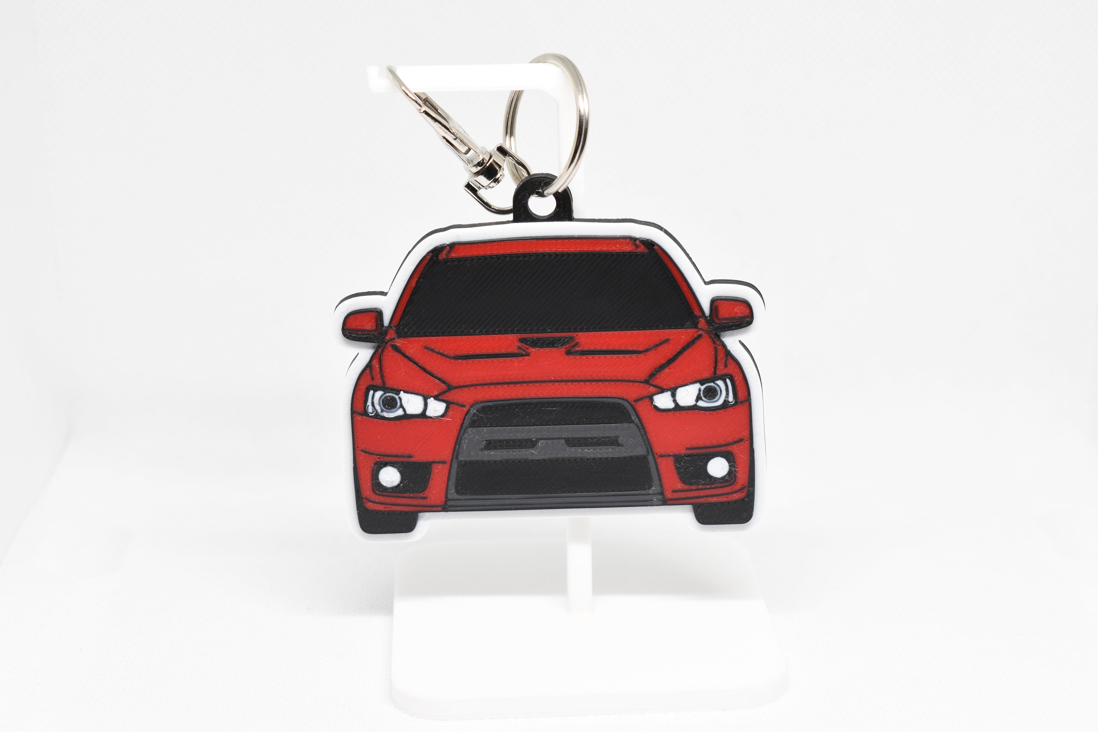 Pocket Motors Evo 10 keychain displayed on a white stand with metal ring and clip.