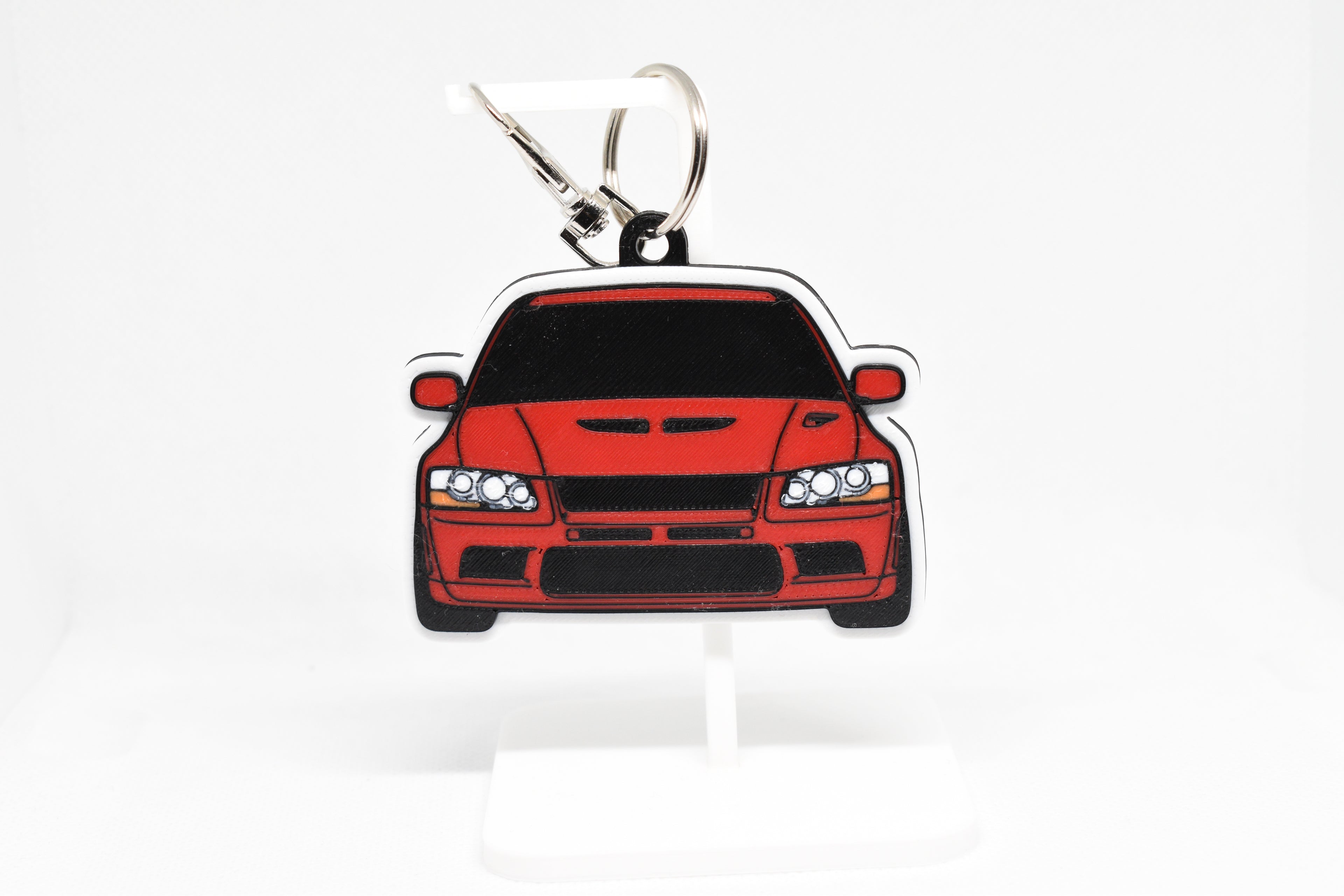 Pocket Motors Evo 7 keychain displayed on a white stand with metal ring and clip.