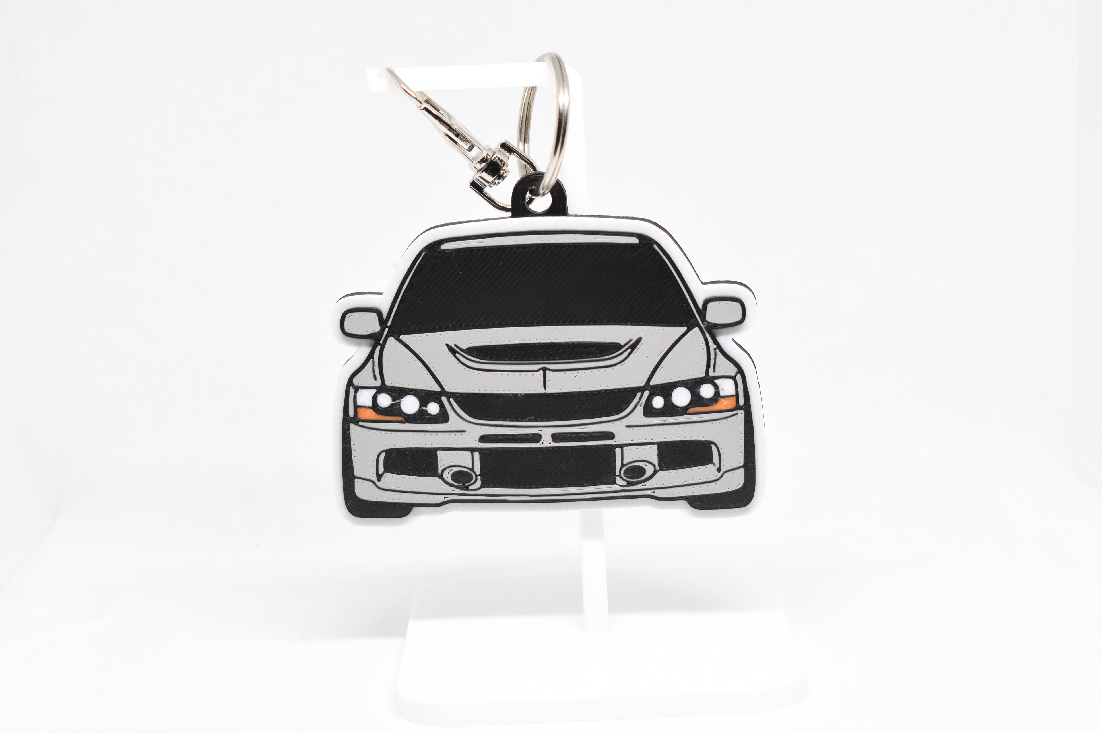 Pocket Motors Evo 9 keychain displayed on a white stand with metal ring and clip.