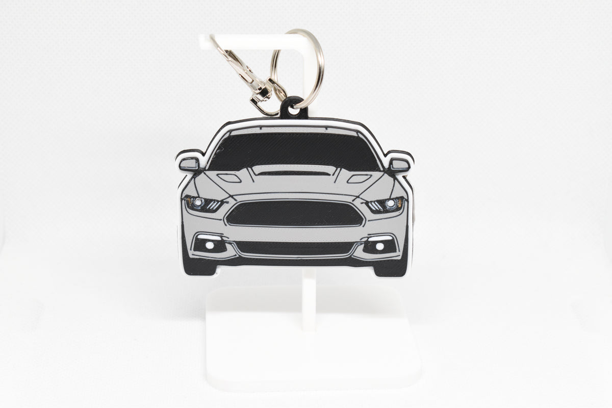 Pocket Motors Ford Mustang S550 keychain displayed on a white stand with metal ring and clip.