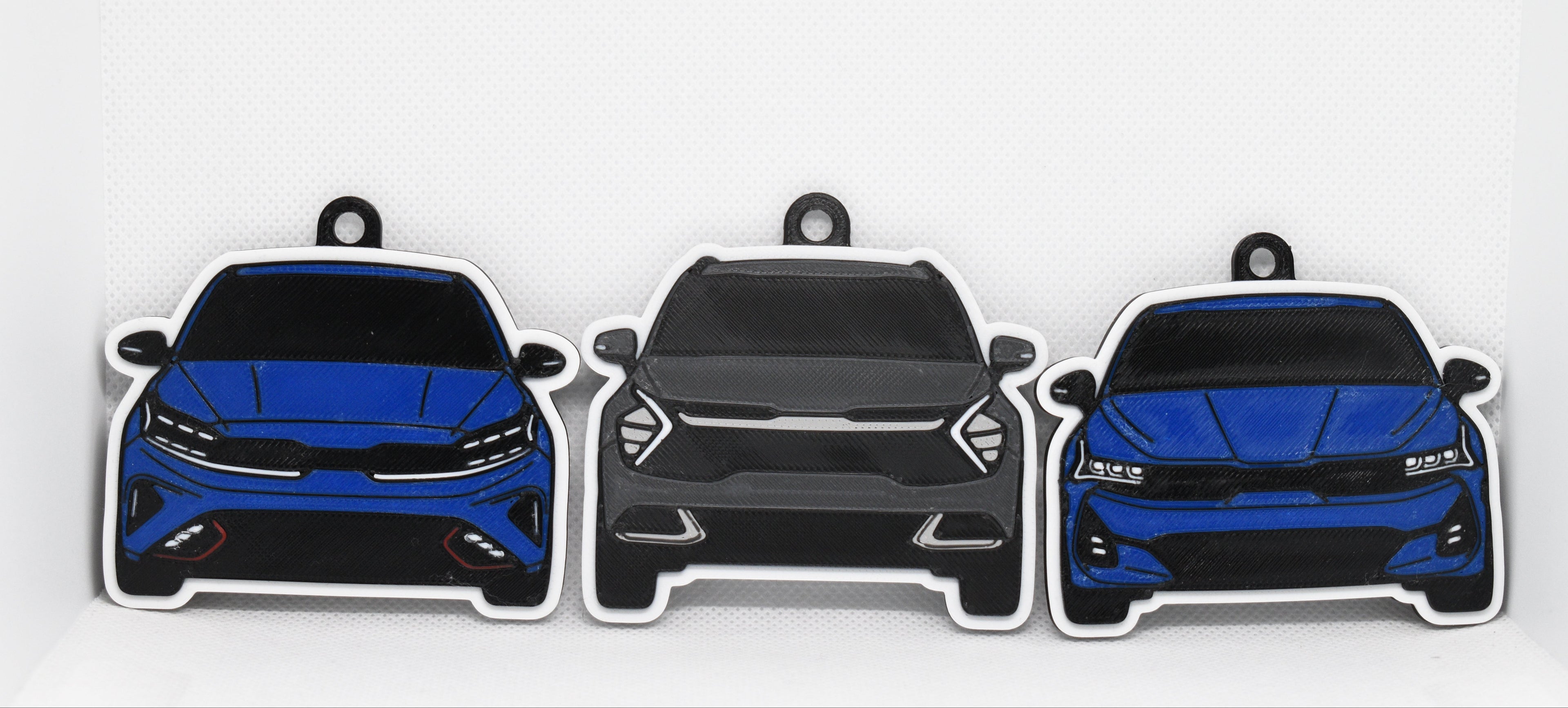 Pocket Motors Forte GT, K5, and Sportage keychains displayed together on a white background.