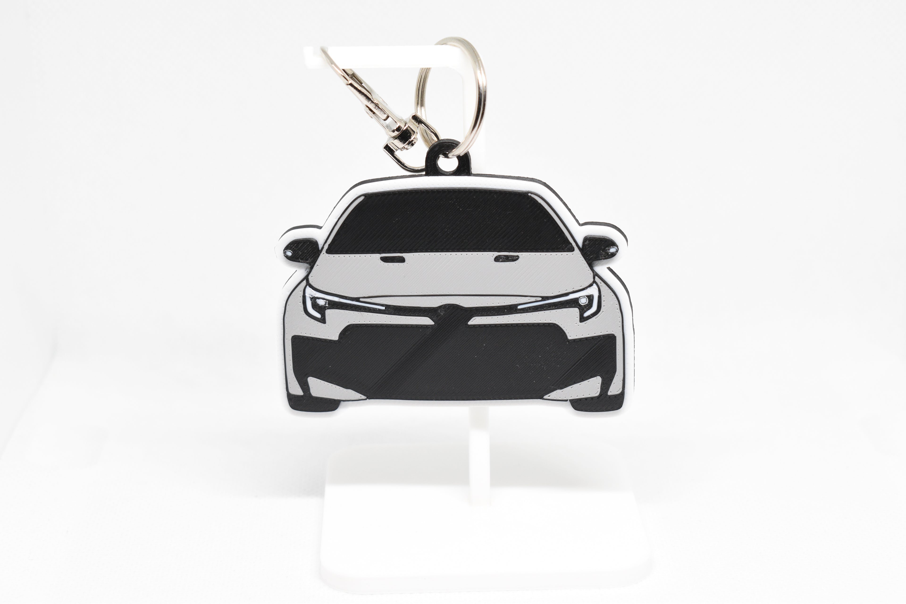 Pocket Motors GR Corolla facelift keychain displayed on a white stand with metal ring and clip.