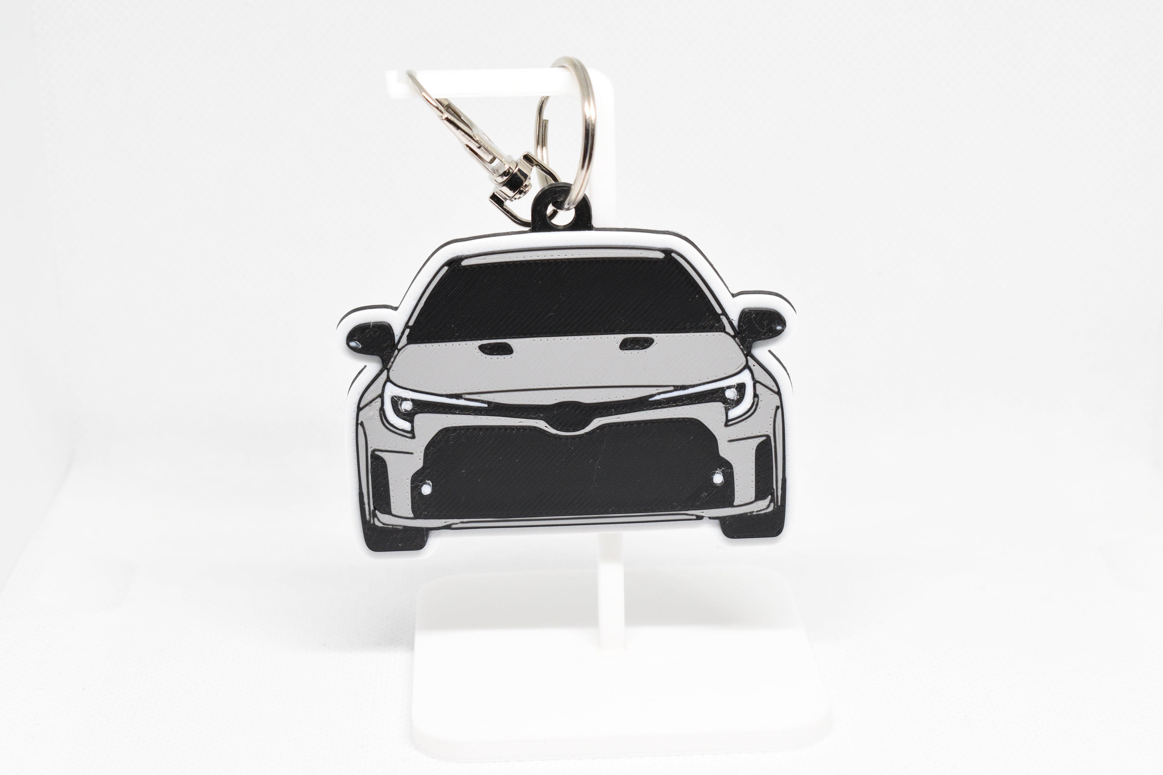Pocket Motors GR Corolla pre‑facelift keychain displayed on a white stand with metal ring and clip.