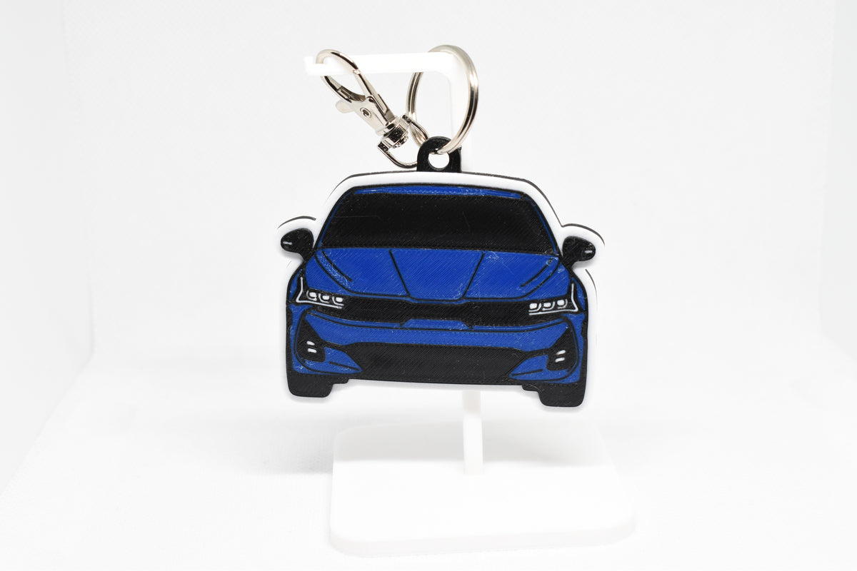 Pocket Motors Kia K5 keychain displayed on a white stand with metal ring and clip.