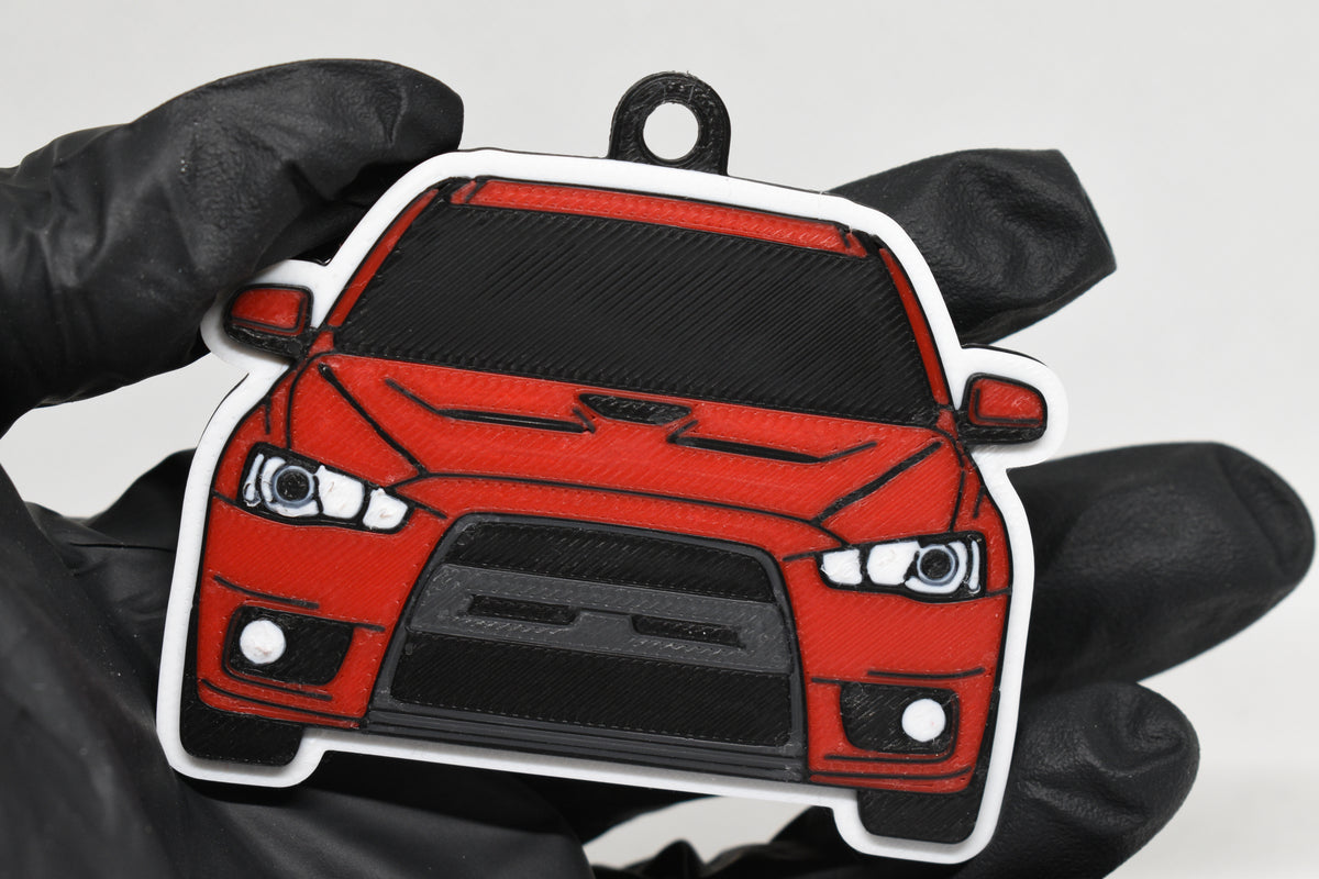 3D printed red Mitsubishi Lancer Evolution 10 keychain held in hand, front view detail by LayerPlay Pocket Motors