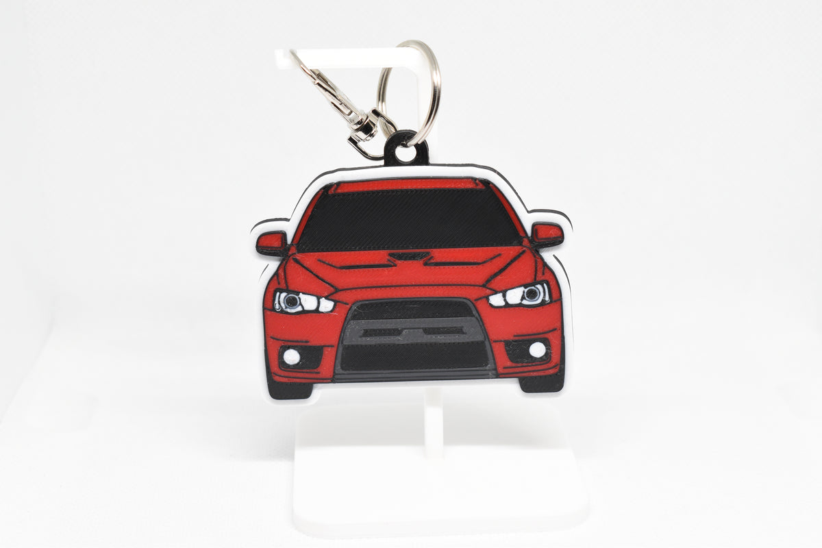 Pocket Motors Mitsubishi Lancer Evolution 10 keychain displayed on a white stand with metal ring and clip.