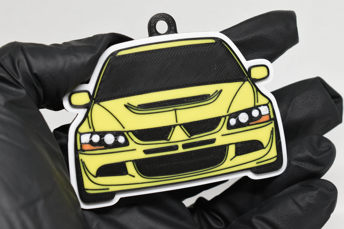 3D printed yellow Mitsubishi Lancer Evolution 8 keychain held in hand, front view detail by LayerPlay Pocket Motors