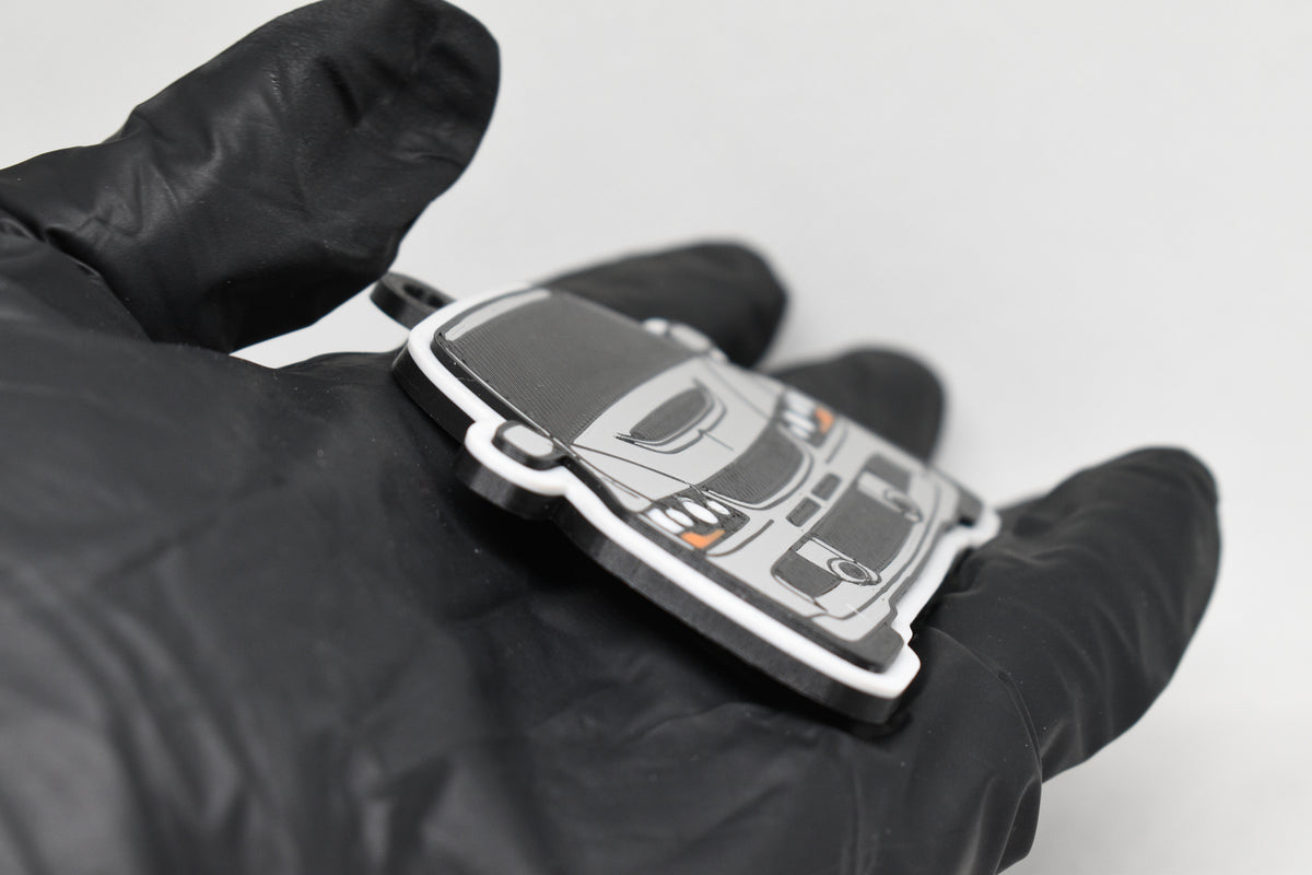 Side angle view showing 3D layered detail of light gray Mitsubishi Lancer Evolution 9 keychain by LayerPlay Pocket Motors