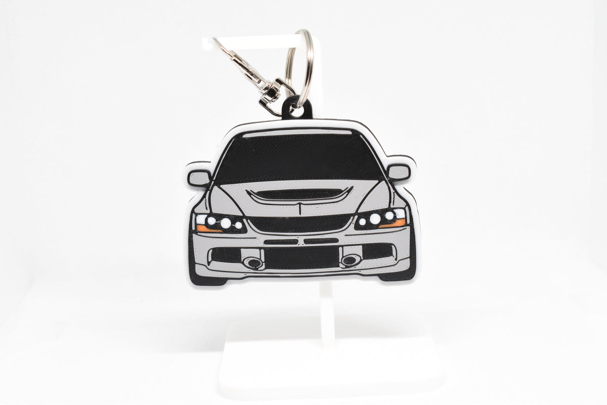 Pocket Motors Mitsubishi Lancer Evolution 9 keychain displayed on a white stand with metal ring and clip.