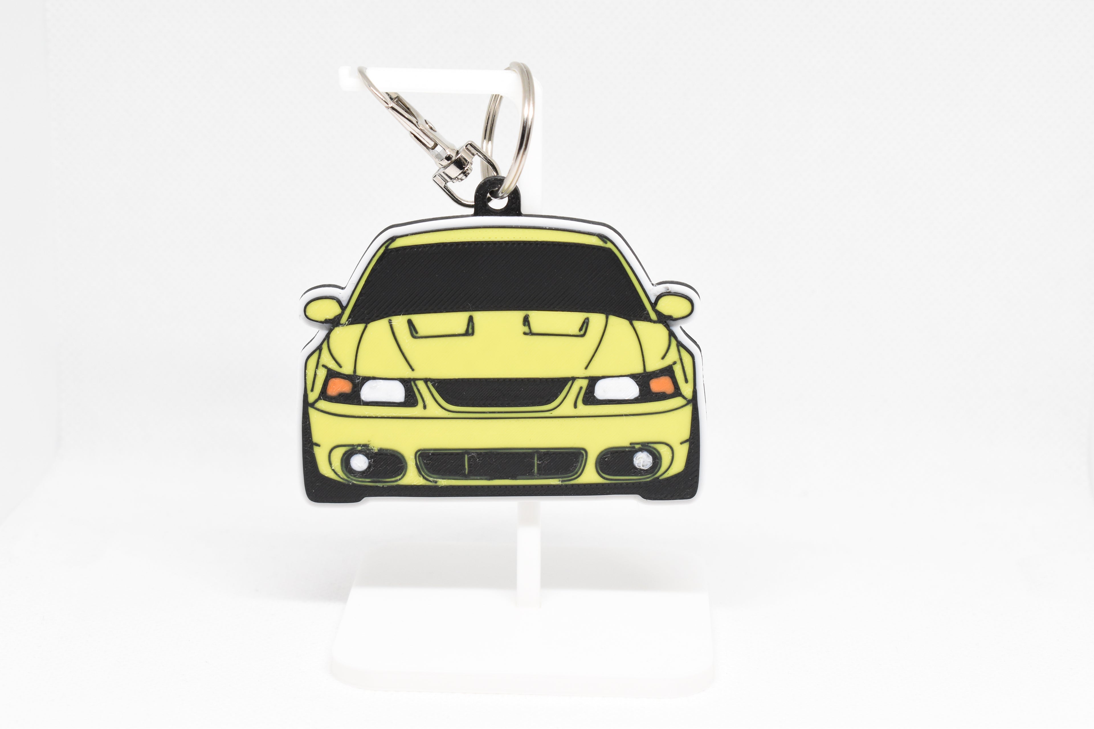 Pocket Motors Mustang Cobra SN95 facelift keychain displayed on a white stand with metal ring and clip.