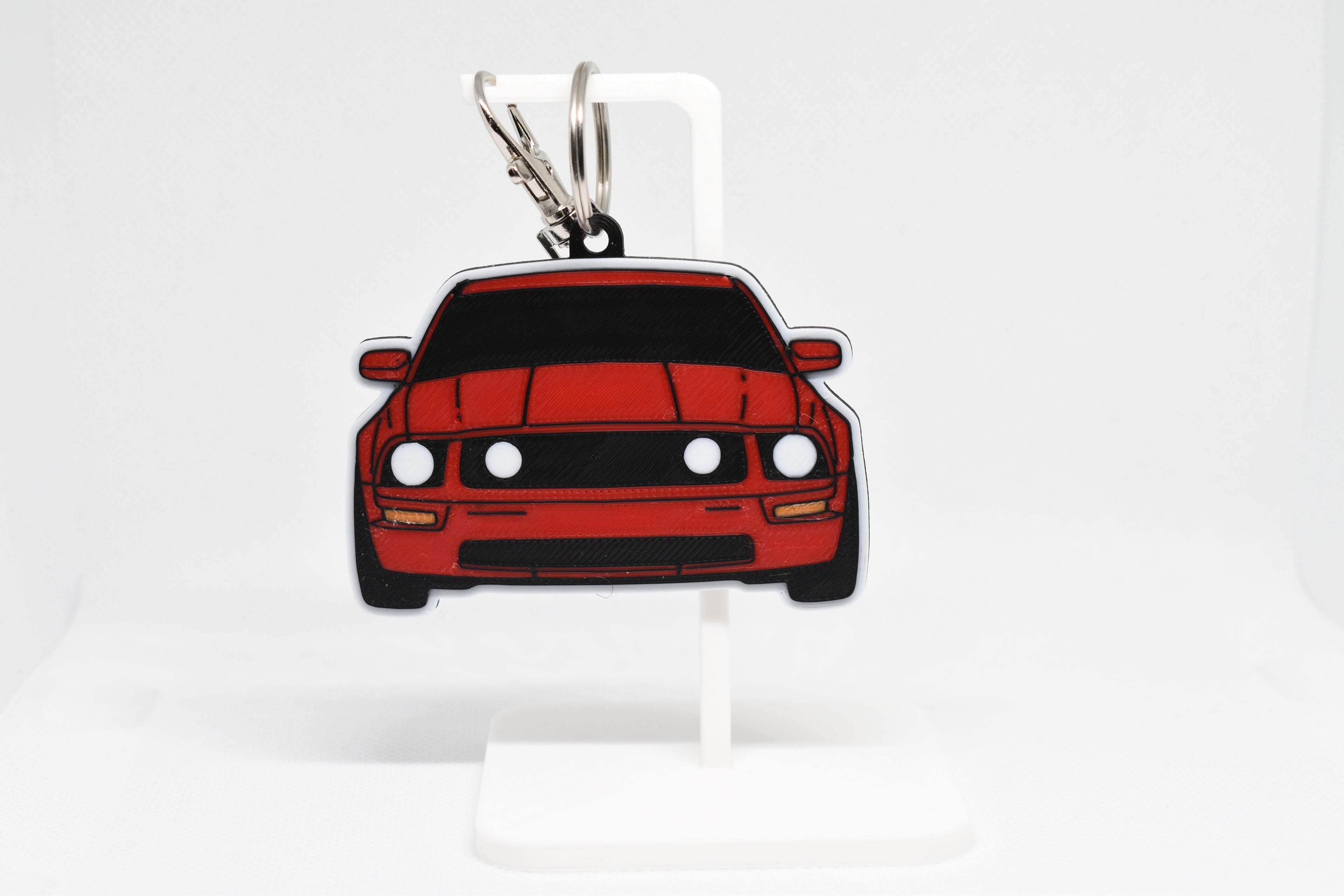 Pocket Motors Mustang S197 keychain displayed on a white stand with metal ring and clip.