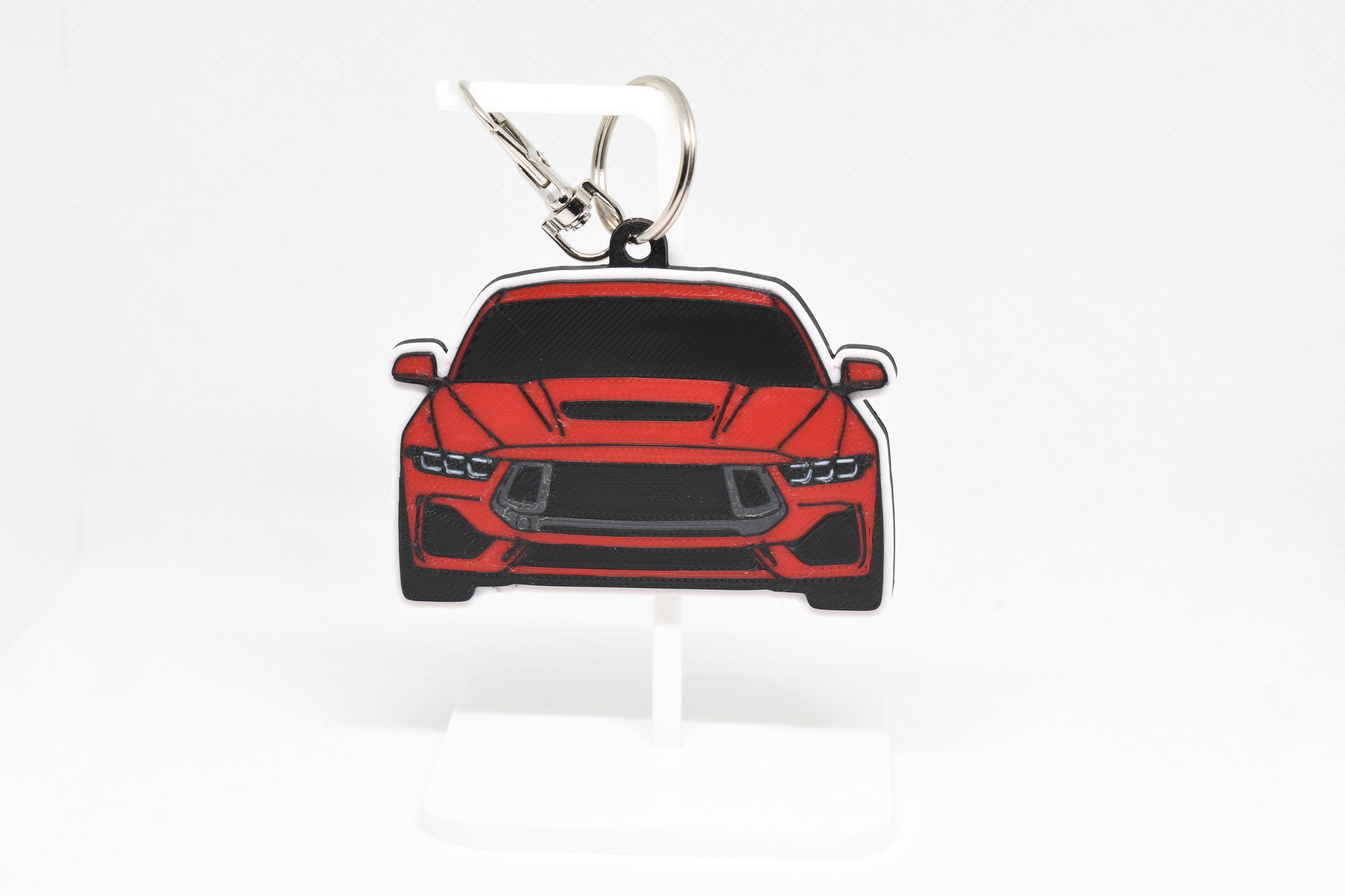 Pocket Motors Mustang S650 keychain displayed on a white stand with metal ring and clip.