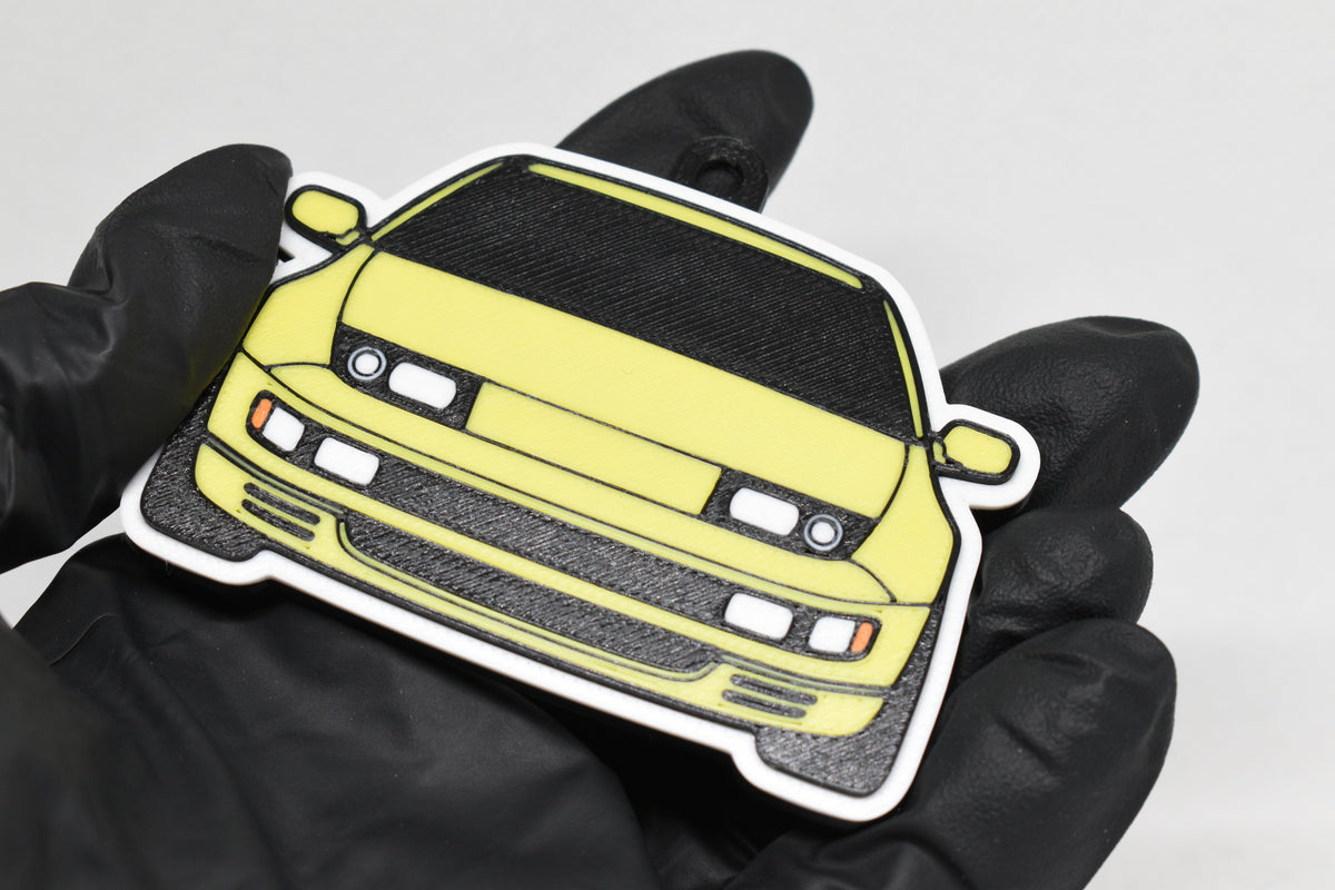 3D printed yellow Nissan 300ZX keychain held in hand, front view detail by LayerPlay Pocket Motors