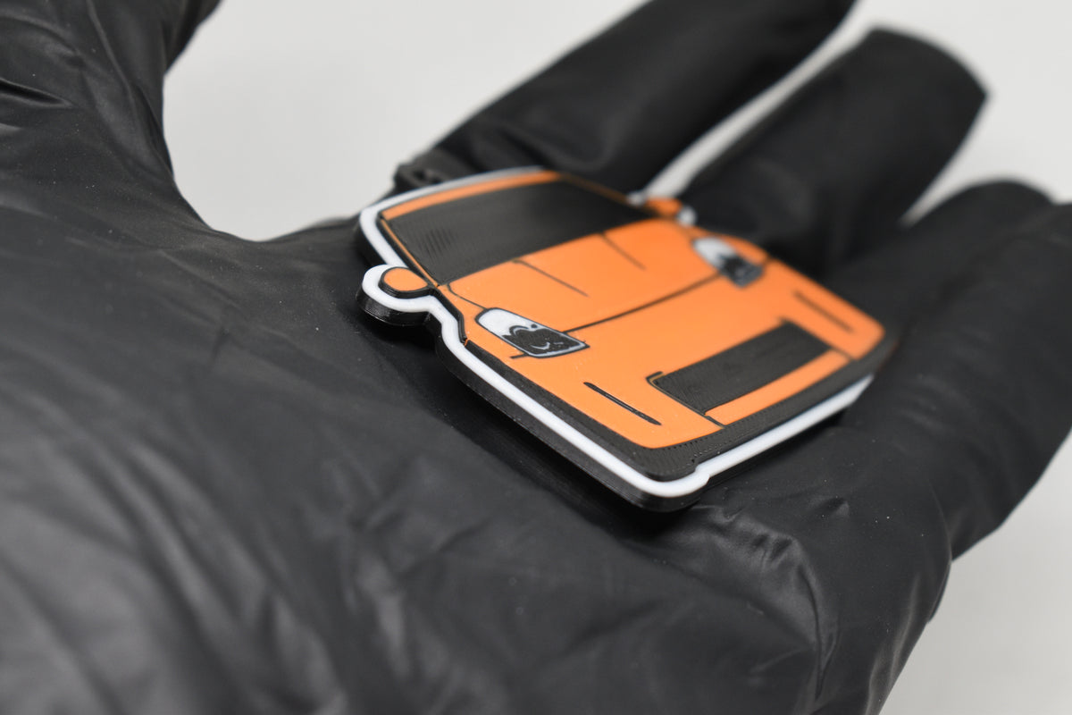 Side angle view showing 3D layered detail of orange Nissan 350Z Z33 keychain by LayerPlay Pocket Motors