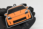 3D printed orange Nissan 350Z Z33 keychain held in hand, front view detail by LayerPlay Pocket Motors