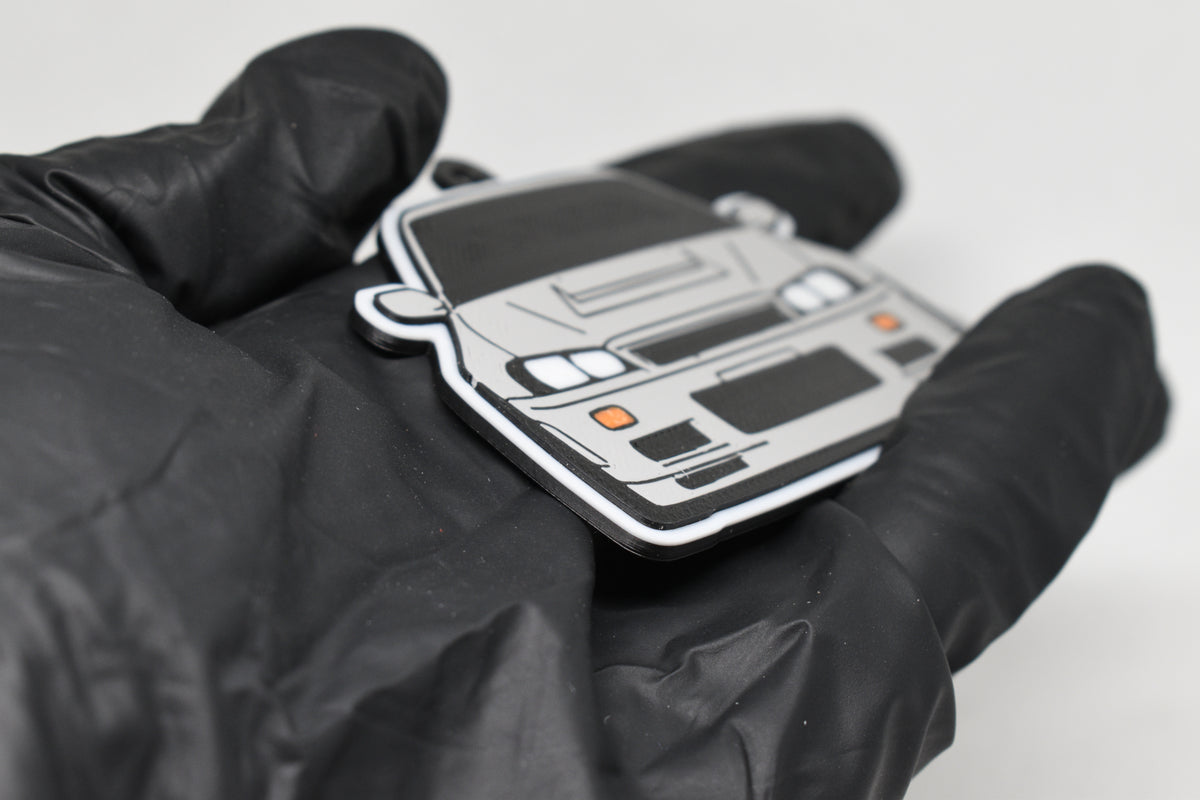 Side angle view showing 3D layered detail of light gray Nissan Skyline GT-R R34 keychain by LayerPlay Pocket Motors