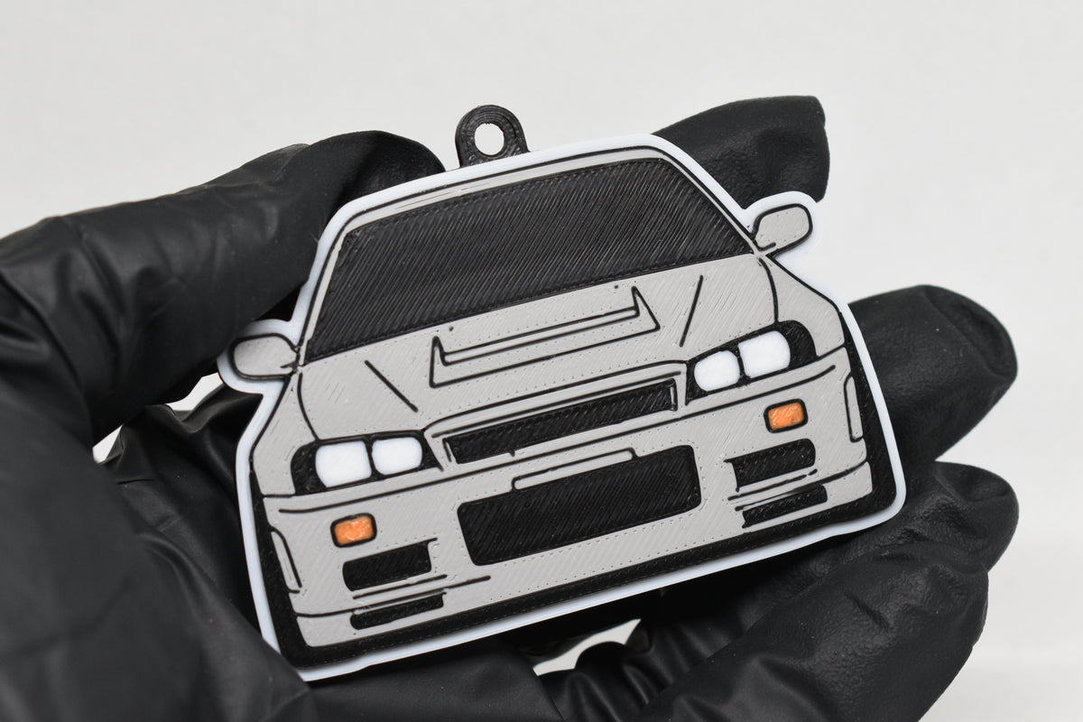 3D printed light gray Nissan Skyline GT-R R34 keychain held in hand, front view detail by LayerPlay Pocket Motors