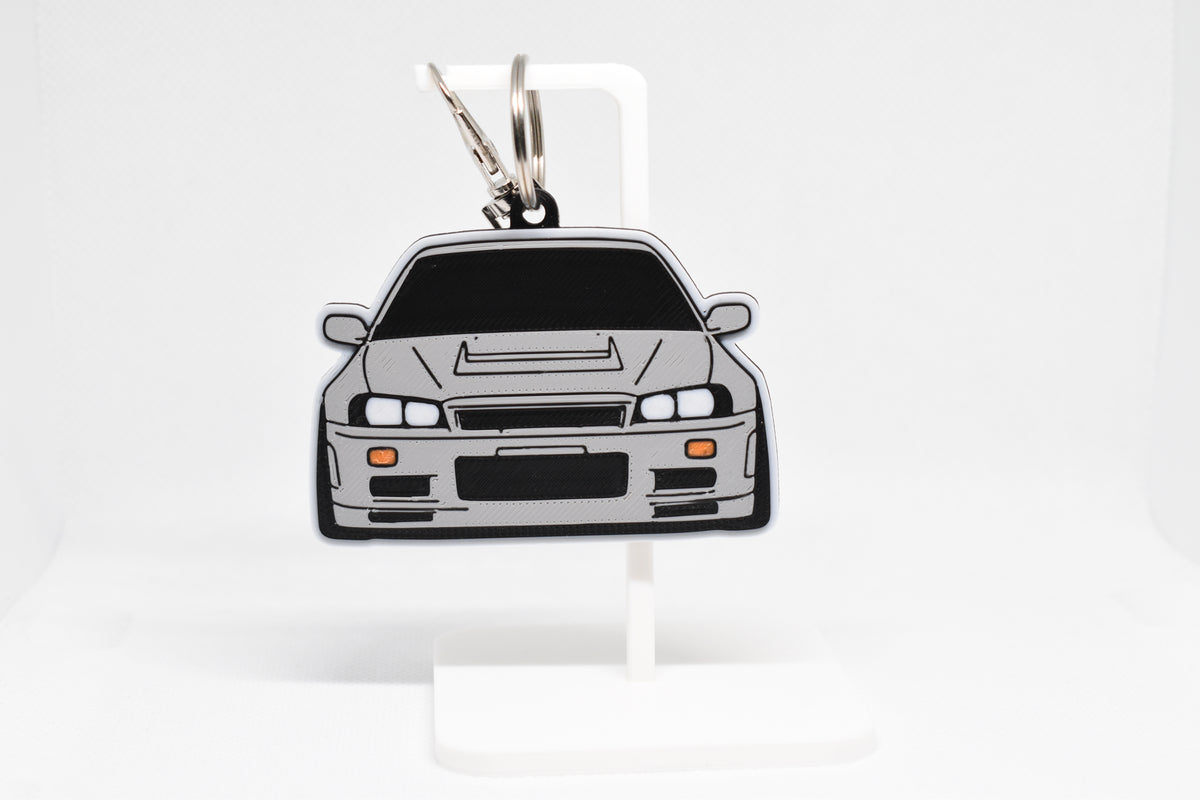Pocket Motors Nissan Skyline GTR R34 keychain displayed on a white stand with metal ring and clip.