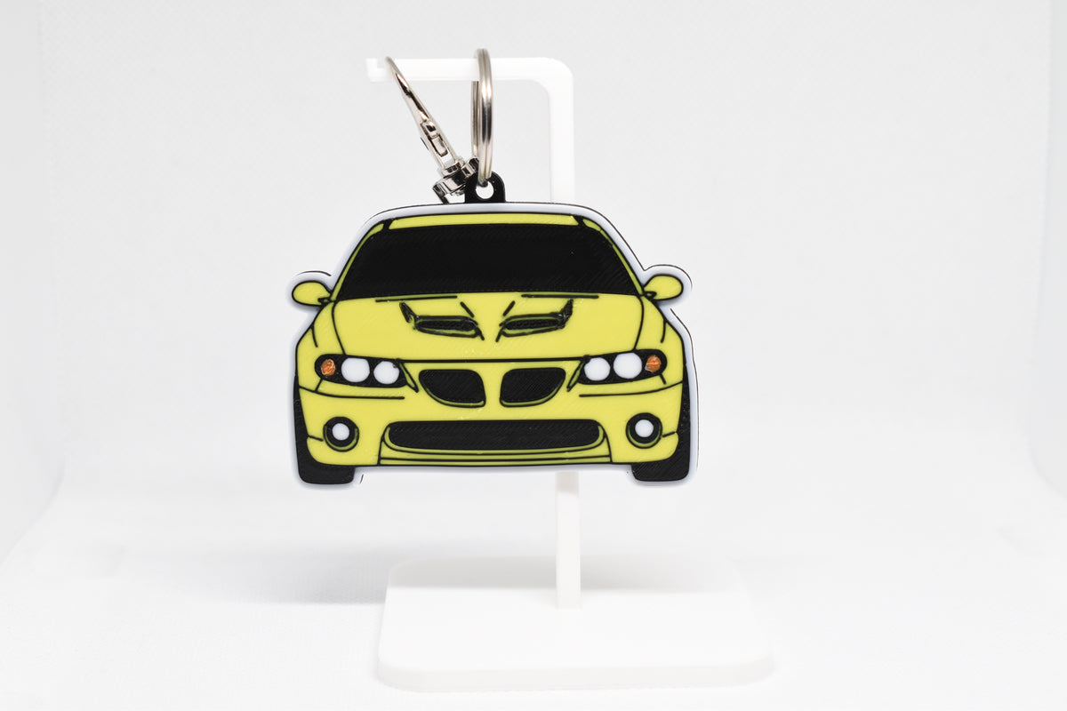 Pocket Motors Pontiac GTO 5th Gen keychain displayed on a white stand with metal ring and clip.