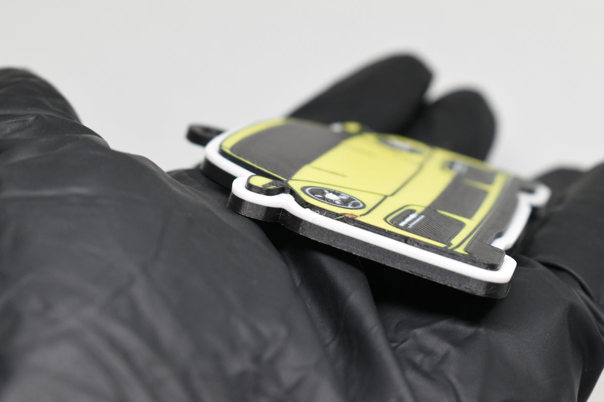 Side angle view showing 3D layered detail of yellow Porsche 911 Turbo S keychain by LayerPlay Pocket Motors