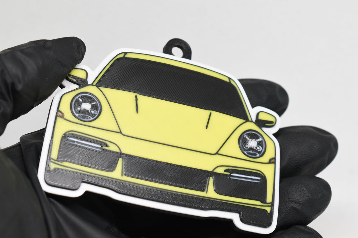 3D printed yellow Porsche 911 Turbo S keychain held in hand, front view detail by LayerPlay Pocket Motors