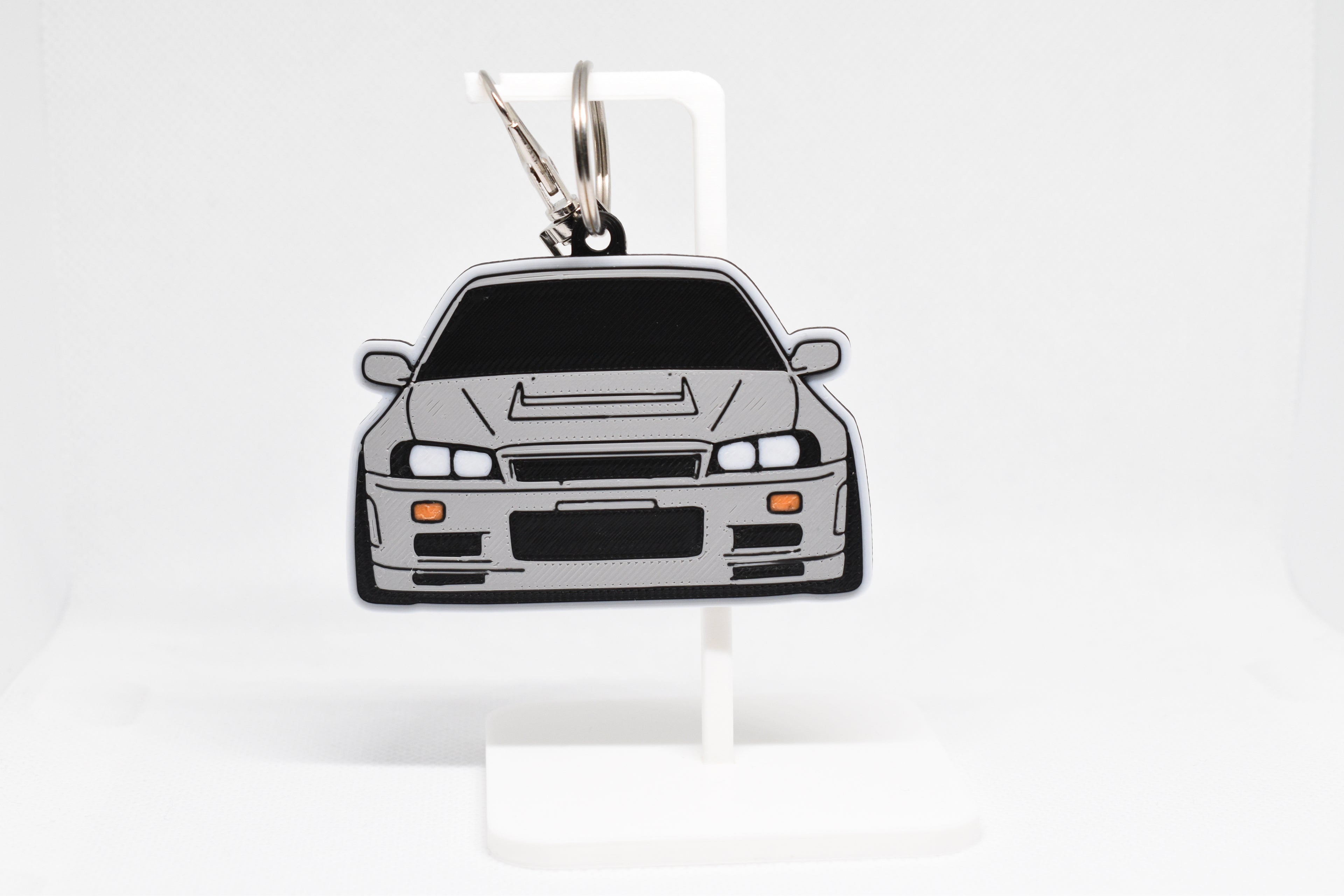 Pocket Motors Skyline GT‑R R34 keychain displayed on a white stand with metal ring and clip.