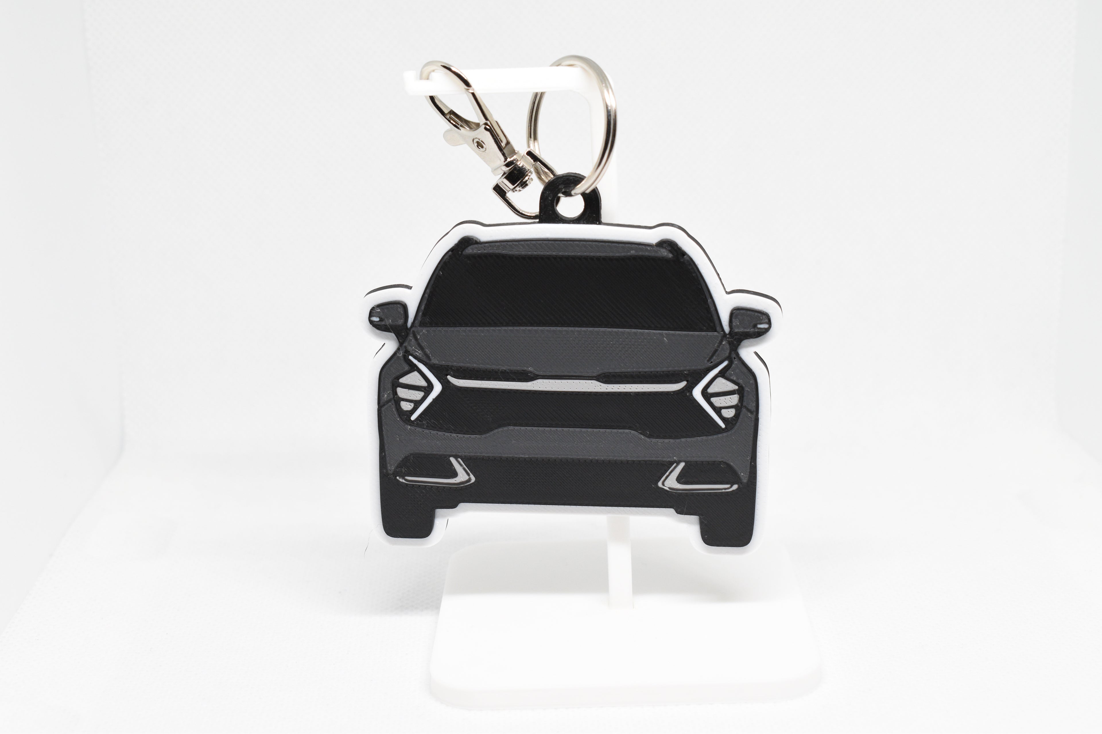 Pocket Motors Sportage keychain displayed on a white stand with metal ring and clip.