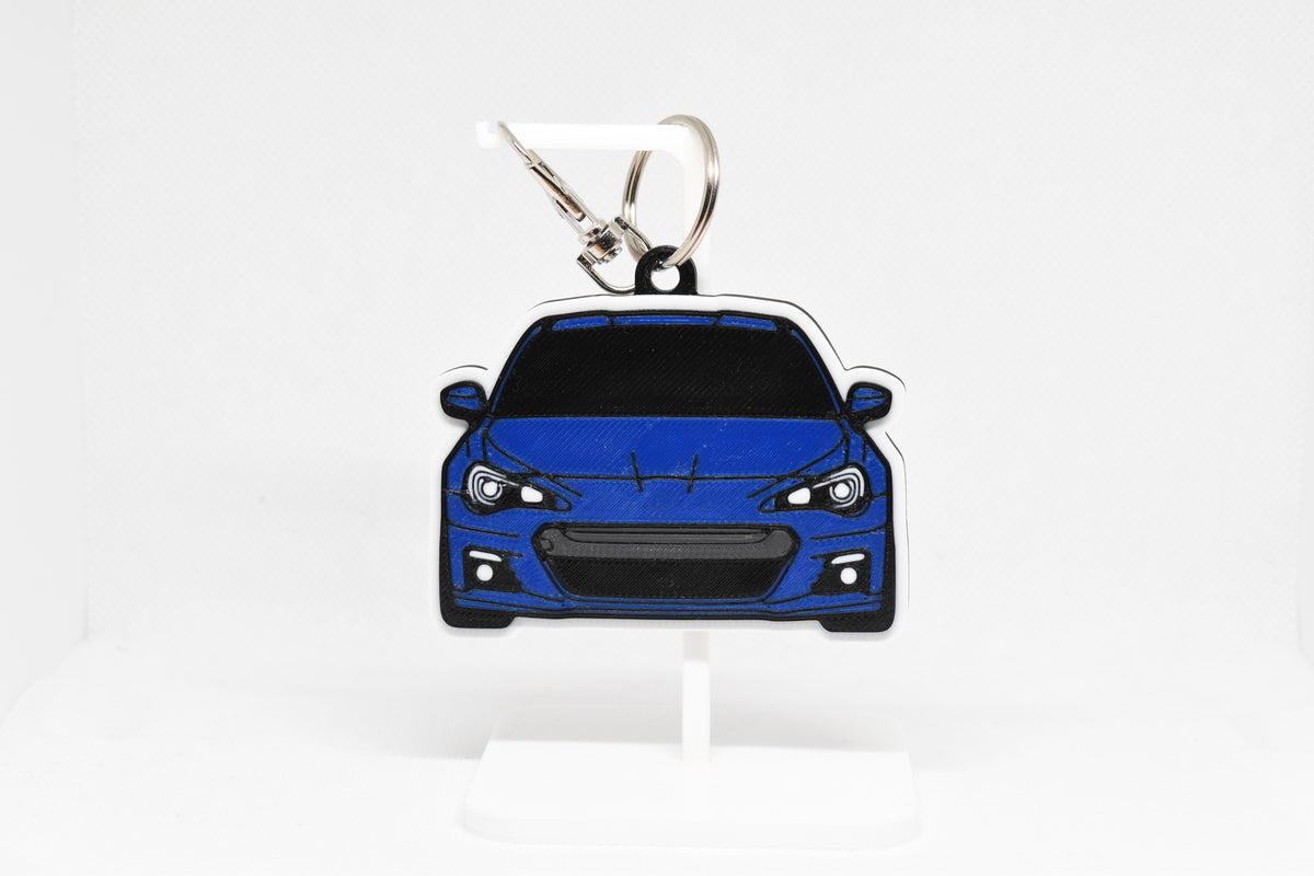 Layerplay Pocket Motors 1st‑gen Subaru BRZ 3D printed keychain displayed on a white stand.