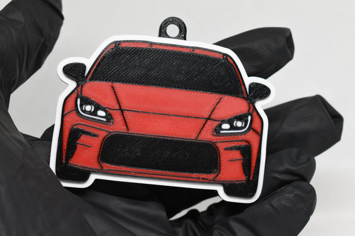 3D printed red Toyota GR86 keychain held in hand, front view detail by LayerPlay Pocket Motors