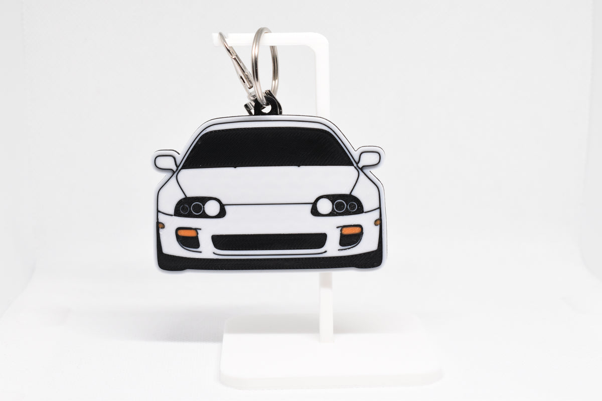 Pocket Motors Toyota Supra MK4 keychain displayed on a white stand with metal ring and clip.