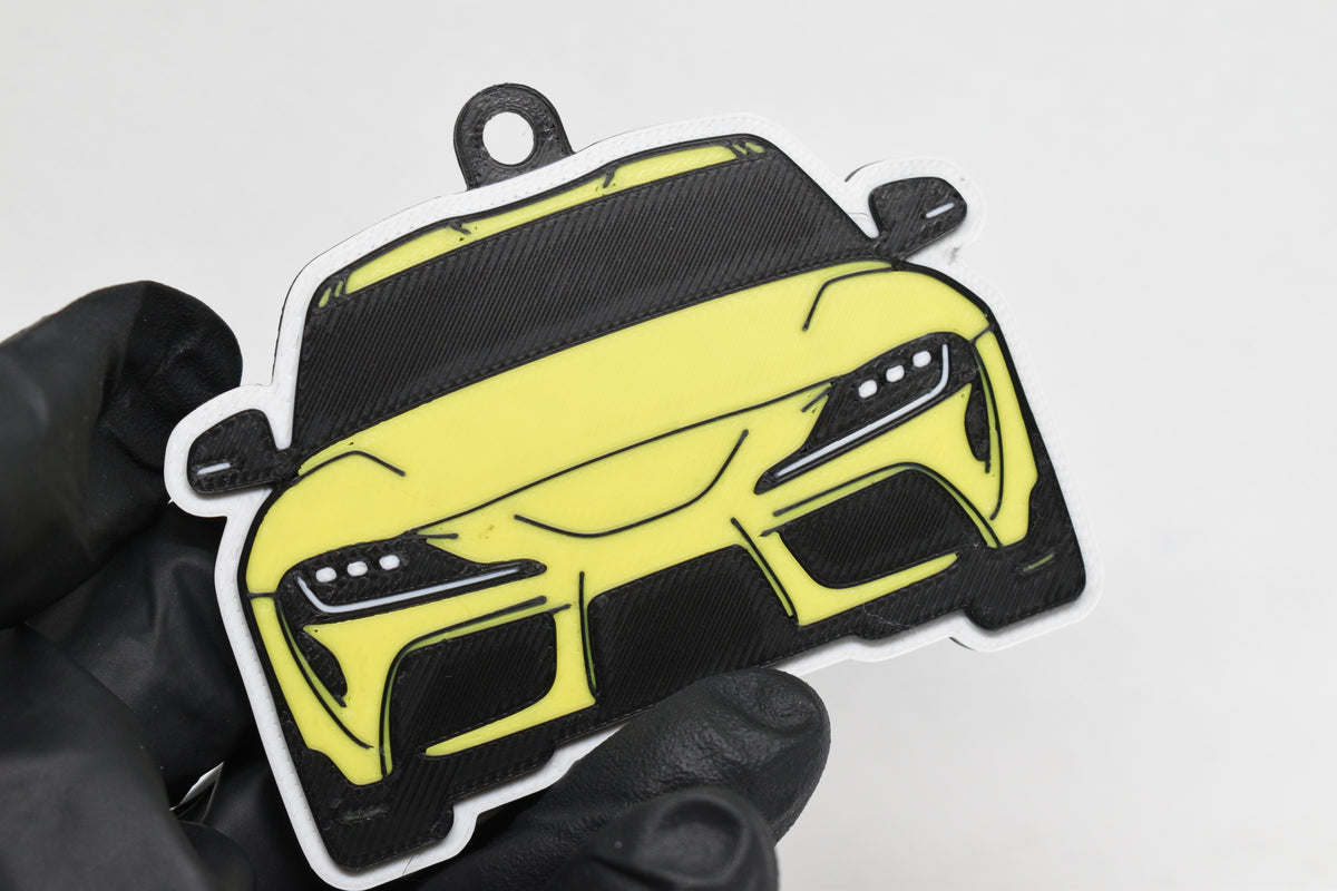 3D printed yellow Toyota Supra Mk5 keychain held in hand, front view detail by LayerPlay Pocket Motors