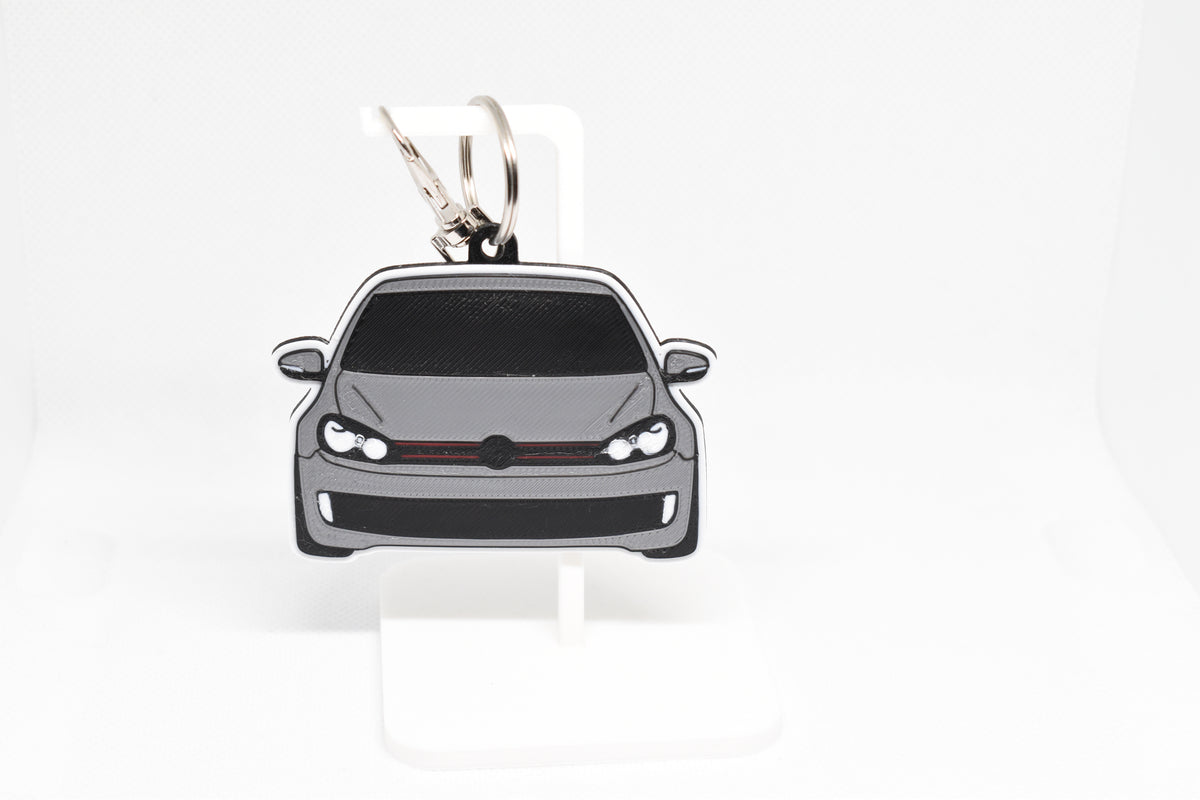 Pocket Motors Volkswagen GTI MK6 keychain displayed on a white stand with metal ring and clip.