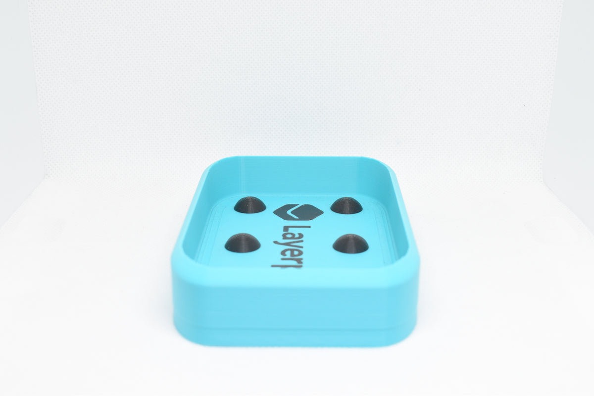 Low side angle studio view of cyan rectangular soap holder with raised domino nubs by LayerPlay Solara