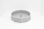Front angle studio shot of grey octagonal soap holder resting inside white drip tray base by LayerPlay Solara
