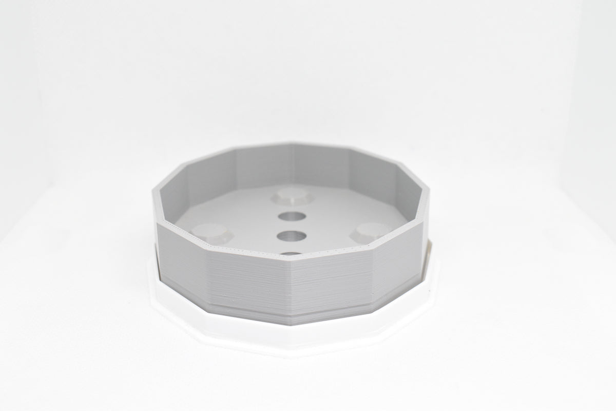 Front angle studio shot of grey octagonal soap holder resting inside white drip tray base by LayerPlay Solara